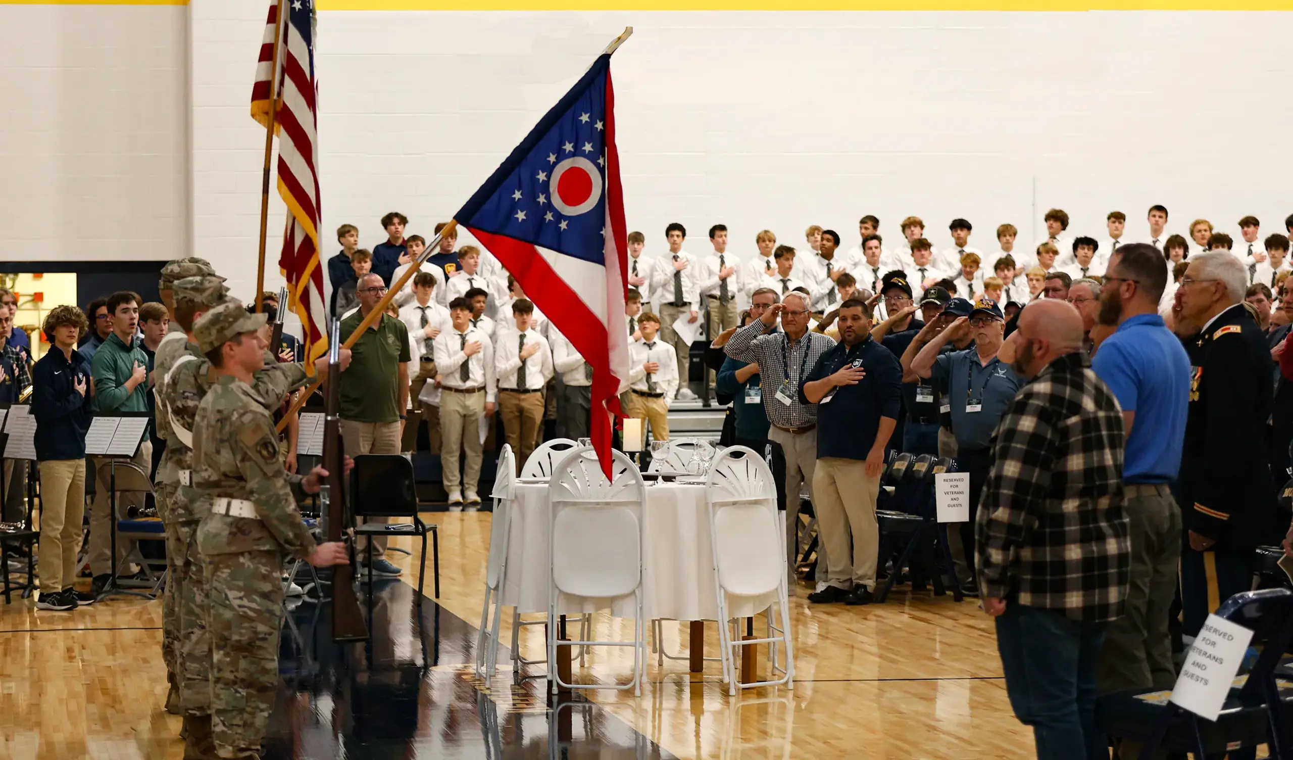 An audience saluting at a Veterans Day assembly